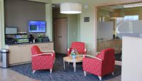 Sitting area and internet coffee bar with video display fill one part of the Claremont Savings&rsquo; &ldquo;small-footprint&rdquo; branch. Private room behind the glass has videoconferencing set-up.
